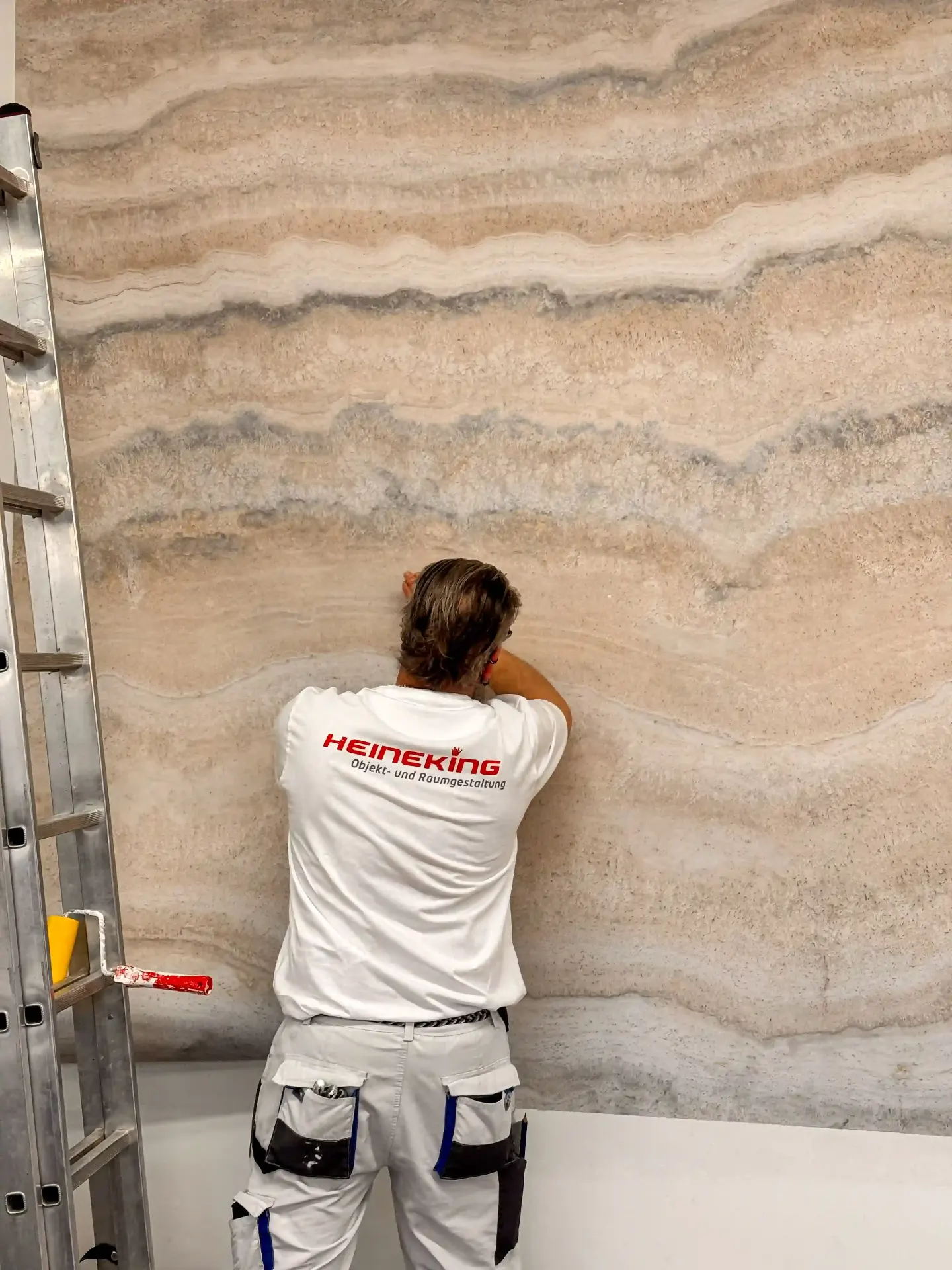 Heineking Mitarbeiter beim Tapezieren einer Marmoroptik-Wand